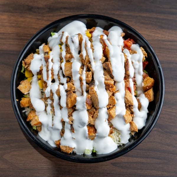 Habaneros Fresh Mexican Grill's burrito bowl with chicken, corn, and white sauce on a wooden table.